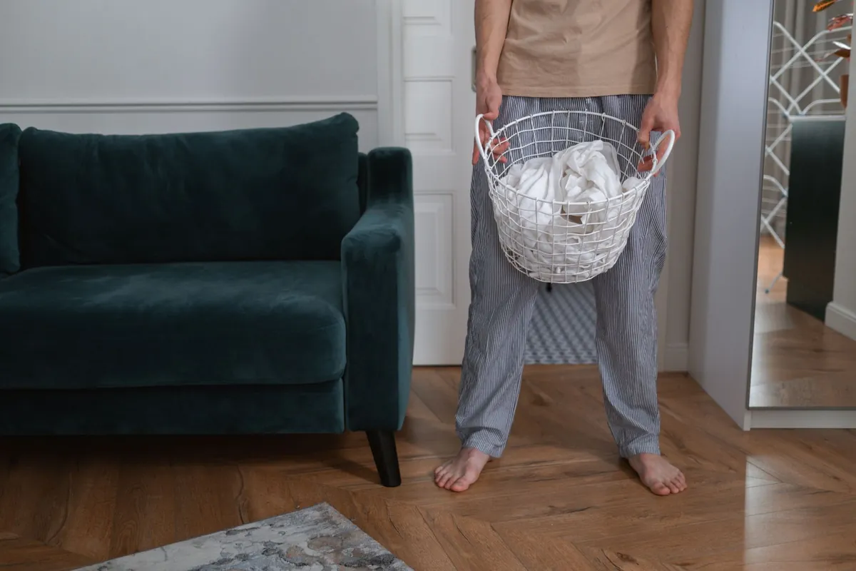 Persona en su casa sosteniendo un canasto con ropa